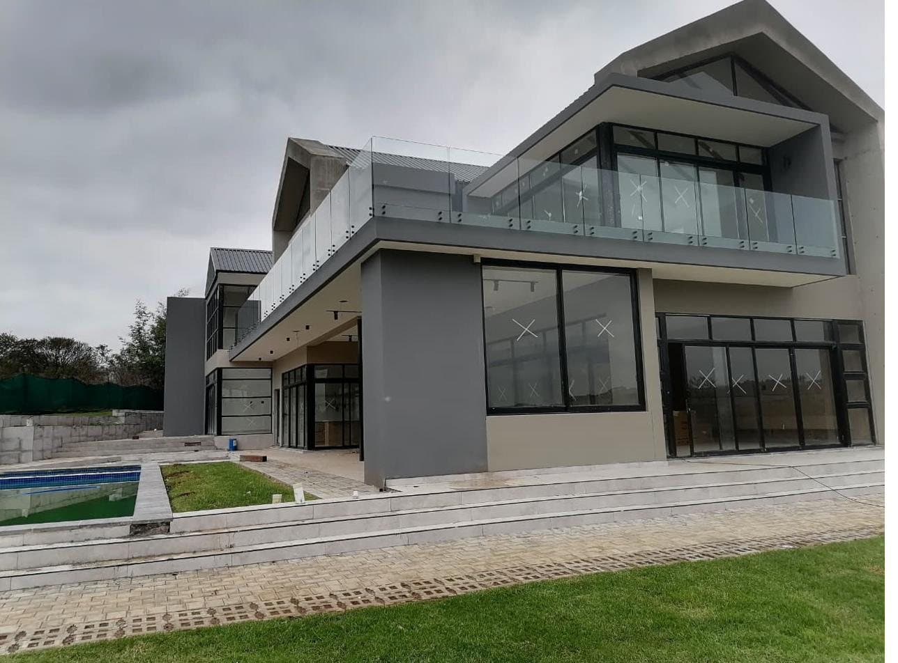 Large modern double-storey home with a sweeping frameless glass balustrade along the upper balcony