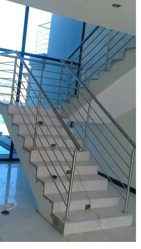 Stainless steel rod balustrade on a tiled interior staircase with glass landing above
