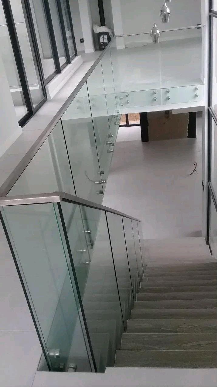 Frameless glass balustrade running alongside a timber staircase inside a modern home